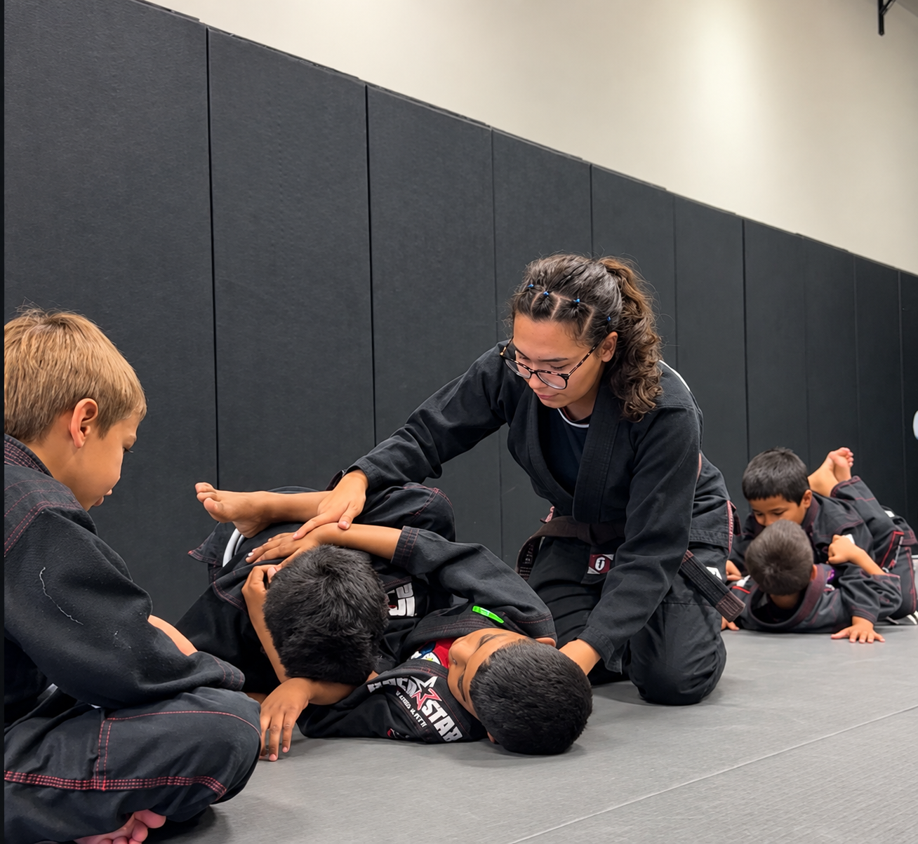 Professor Maddie Wolfe guiding children during a Brazilian Jiu-Jitsu class